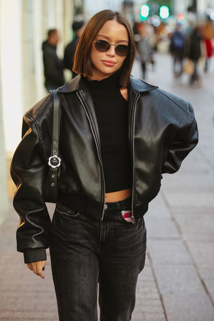 who-we-are Stylish woman in leather jacket struts confidently along bustling urban street.