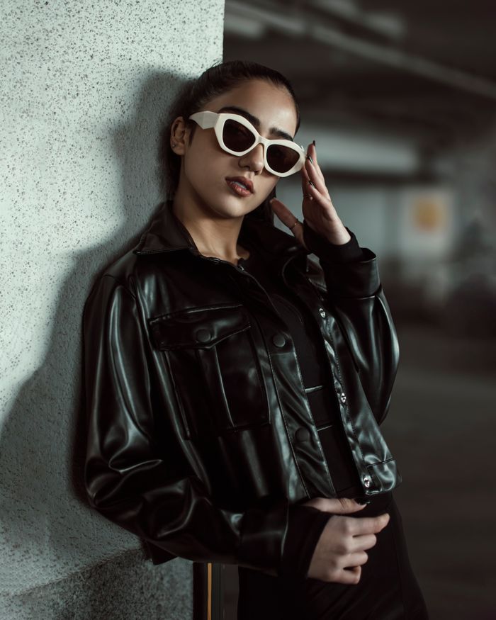Mastering the First Impression: Your intriguing post title goes here Fashionable woman in black leather leaning on a wall, exuding confidence.